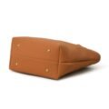 Close-up view of the bottom of a Tan leather tote bag, showcasing its sturdy and flat base, against a white background
