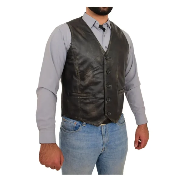 Angled view of a man wearing a nick black vintage leather vest over a light gray button-up shirt, paired with blue jeans and a brown leather belt